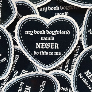 May include: A black heart-shaped sticker with white text that reads "my book boyfriend would NEVER do this to me".