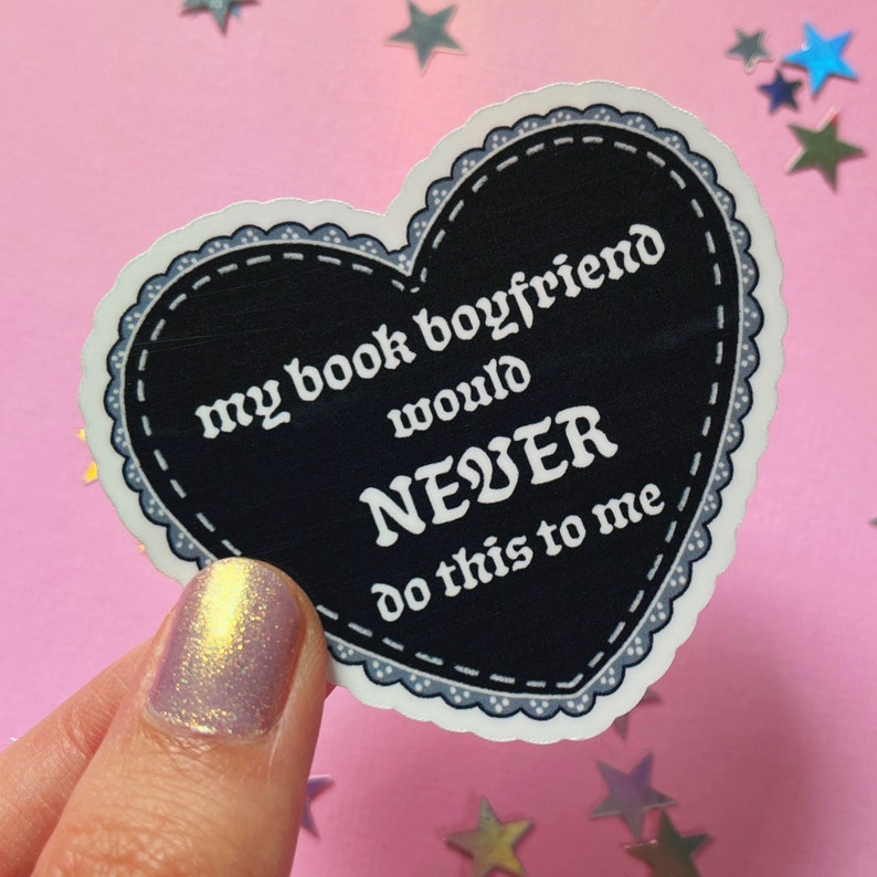 May include: A black heart-shaped sticker with a white border and white text that reads "my book boyfriend would NEVER do this to me".