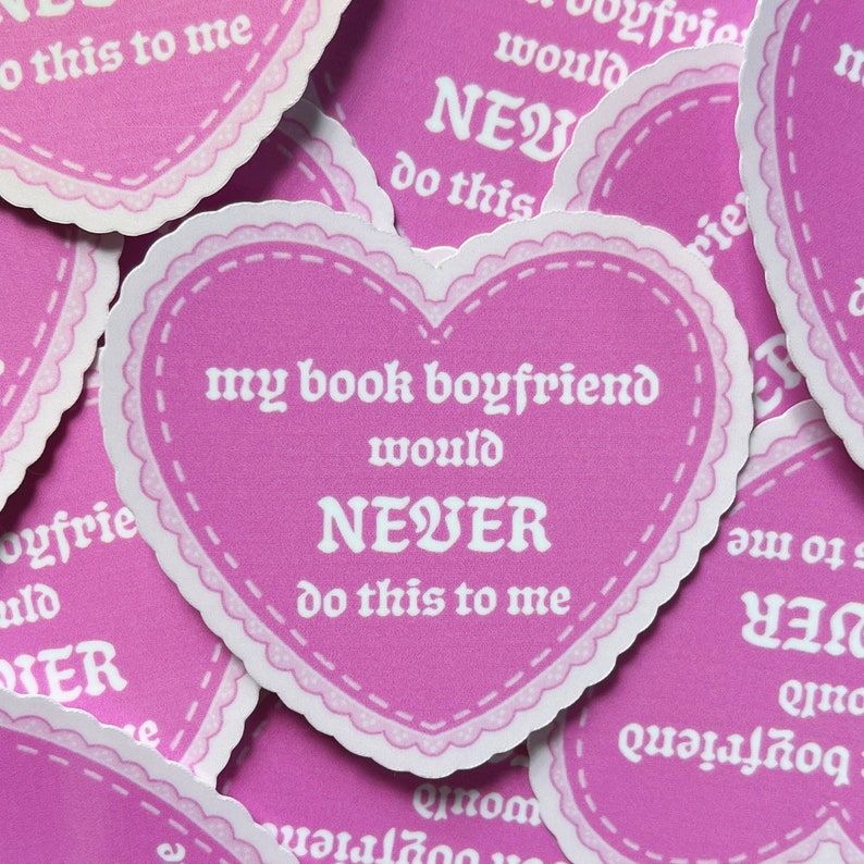 May include: Pink heart-shaped sticker with a white border and white text that reads "My book boyfriend would NEVER do this to me."