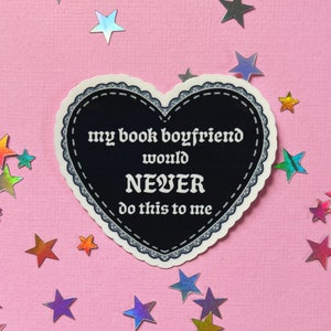 May include: A black heart-shaped sticker with a white lace border. The sticker says "my book boyfriend would NEVER do this to me".