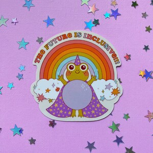 May include: A sticker featuring a frog wearing a wizard hat and a purple cape with stars. The frog is standing in front of a rainbow with the text "The Future is Inclusive!!!" above it.
