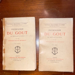 Könnte beinhalten: Zwei Vintage-Buchcover mit dem Titel "Physiologie du Gout" von Brillat-Savarin. Die Cover sind cremefarben mit schwarzem Text und einem dekorativen Anker-Symbol.