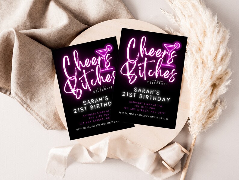 Op de afbeelding: Een zwart-witte uitnodiging met roze neontekst die "Cheers Bitches" en een cocktailglas-icoon toont. De uitnodiging is voor Sarah's 21e verjaardagsparty. Het feest is op zaterdag 3 mei om 19:00 uur in The City Pub, 125 Any Street, Any City. RSVP aan Meg v&oacute;&oacute;r 5 april op 123-456-789.