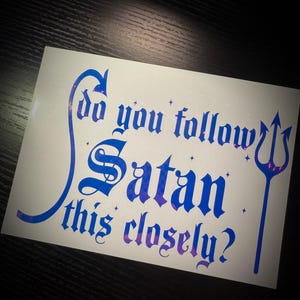 May include: White sticker with blue and purple text that reads "Do you follow Satan this closely?" The design includes a blue arrow, a trident, and small star accents.