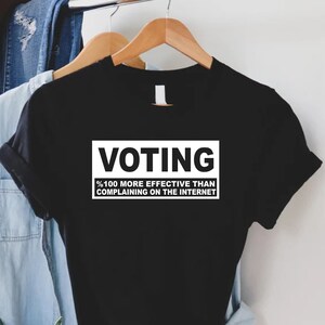 May include: Black t-shirt with white text that reads "Voting %100 more effective than complaining on the internet."