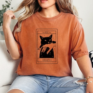 a woman sitting on a couch wearing a t - shirt with a picture of a