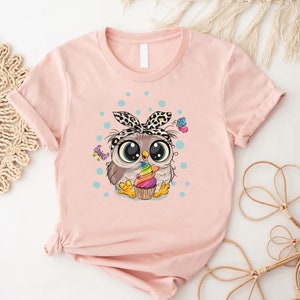a pink shirt with an owl holding a cupcake