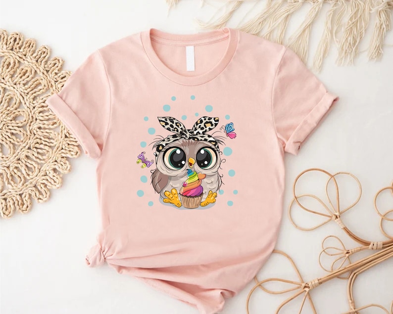 a pink shirt with an owl holding a cupcake