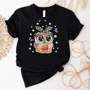 a black shirt with an owl eating a cupcake
