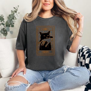 a woman sitting on a couch wearing a t - shirt with a picture of a