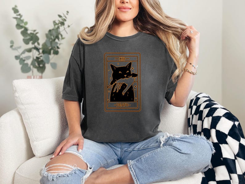 a woman sitting on a couch wearing a t - shirt with a picture of a