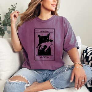 a woman sitting on a couch wearing a t - shirt with a picture of a