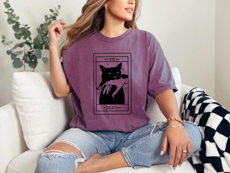 a woman sitting on a couch wearing a t - shirt with a picture of a