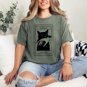 a woman sitting on a couch wearing a t - shirt with a picture of a