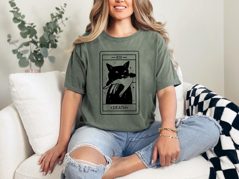 a woman sitting on a couch wearing a t - shirt with a picture of a