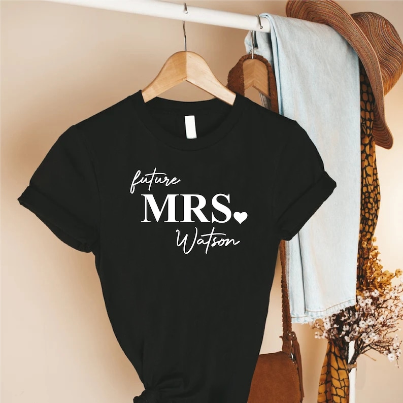 a t - shirt hanging on a rack next to a purse