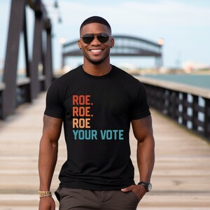 a man in a black t - shirt is standing on a bridge