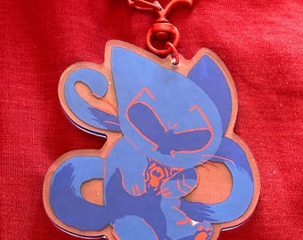May include: A blue cat character keychain with a red bat-shaped clip. The cat is holding a red heart in its paws.