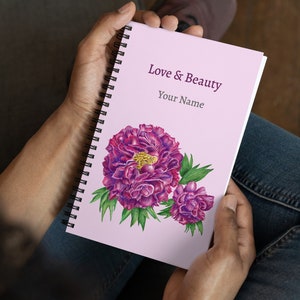 Może przedstawiać: Różowy notes w spirali z nadrukowanym tekstem "Love & Beauty" i "Your Name" na okładce. Notes zawiera akwarelowy rysunek dwóch różowych piwonii z zielonymi liśćmi.