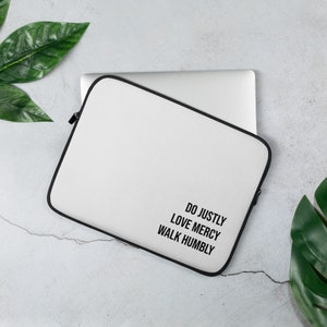 Puede incluir: Funda para portátil blanca con cremallera negra y el texto "Do justly, Love mercy, Walk humbly" impreso en la parte delantera.