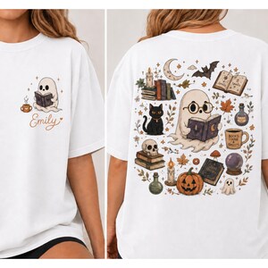 Puede incluir: Una camiseta blanca con un peque&ntilde;o fantasma leyendo un libro y el nombre Emily en el frente. La parte posterior muestra un gr&aacute;fico grande con un fantasma con gafas, un gato negro, una calabaza, libros, una calavera, una bola de cristal y el texto Books Coffee & Ghosts.