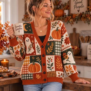 May include: A long-sleeve button-down cardigan featuring a patchwork pattern of pumpkins, ghosts, autumn leaves, and plaid squares in shades of orange, green, and cream. The garment has a V-neckline and ribbed cuffs, with a dark orange trim along the front.