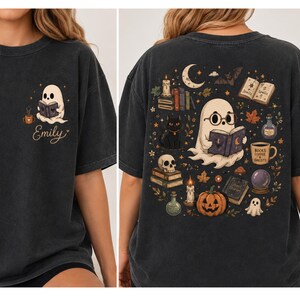 Puede incluir: Una camiseta gris carb&oacute;n con un peque&ntilde;o gr&aacute;fico en el frente de un fantasma leyendo un libro con el nombre Emily y una taza de caf&eacute;. La parte posterior muestra una gran ilustraci&oacute;n de un fantasma leyendo, un gato negro, calabaza y libros.
