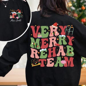 May include: Black sweatshirt with a festive design that says "Very Merry Rehab Team" in colorful retro letters. The design includes Christmas lights, a Santa hat, a walker, a brain, and other holiday and rehabilitation-related symbols.