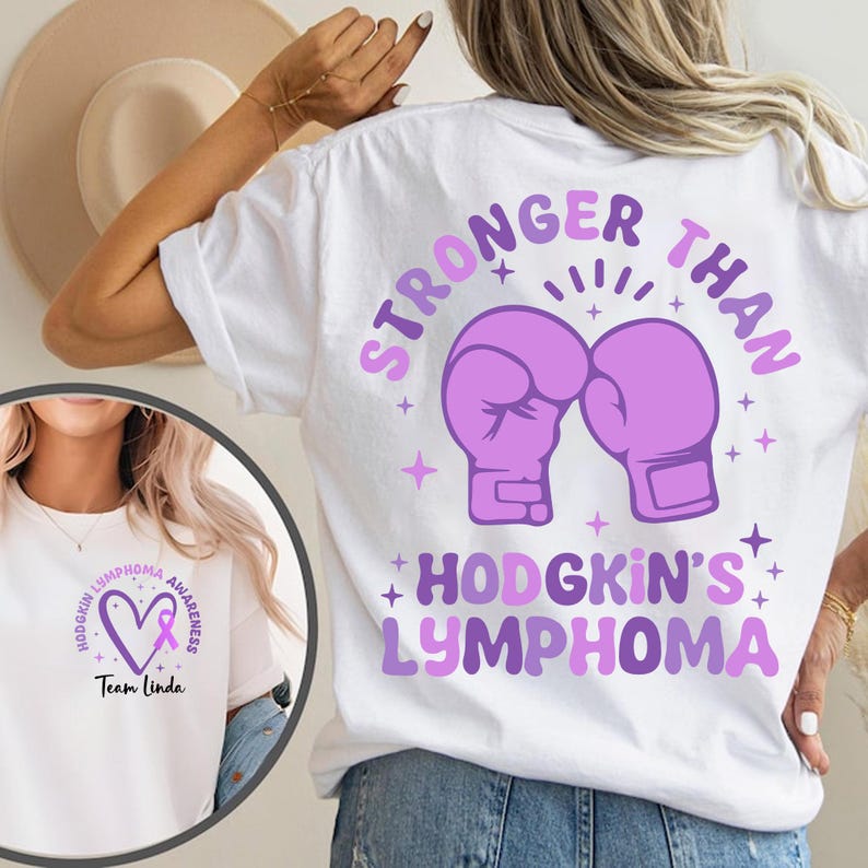 May include: White t-shirt with a design promoting Hodgkin's Lymphoma awareness. The back features purple boxing gloves and the words "STRONGER THAN" above "HODGKIN'S LYMPHOMA." The front has a heart and ribbon with the words "HODGKIN'S LYMPHOMA AWARENESS" and "Team Linda."