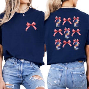 a woman wearing a navy blue t-shirt with pink bows on the back, paired with distressed blue jeans.