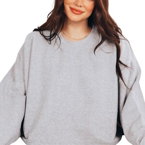 a woman wearing a grey sweatshirt and a black hat