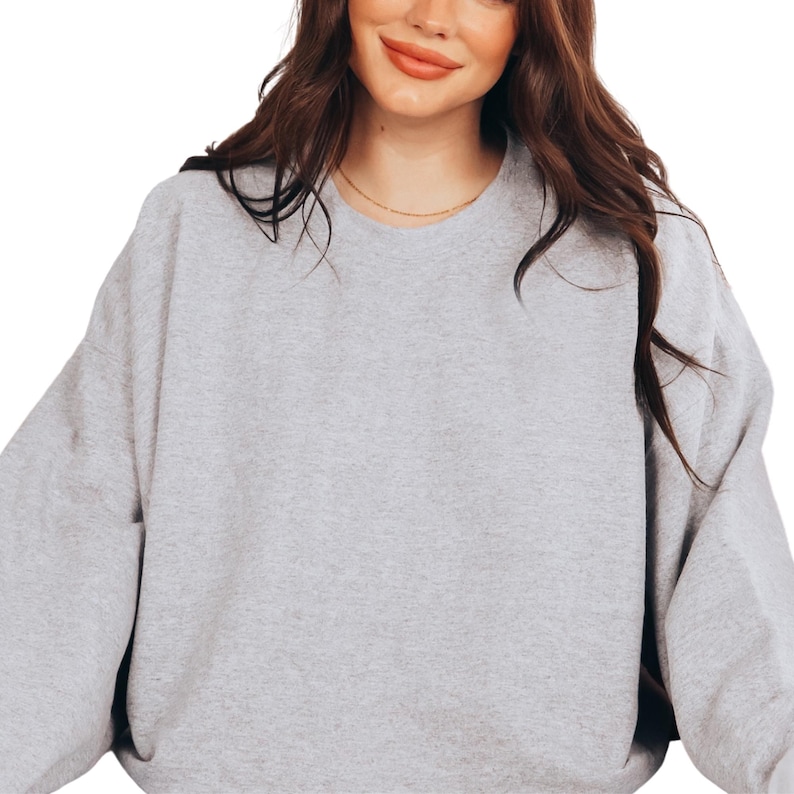 a woman wearing a grey sweatshirt and a black hat