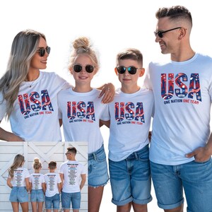 A group of four people, two men and two women, wearing matching white t-shirts with the text "USA ONE NATION ONE TEAM" printed on them.
