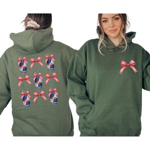 a woman wearing a green hoodie with pink bows on the back.