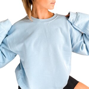 a woman wearing a blue sweatshirt and black shorts