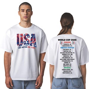 A man wearing a white t-shirt with the text "USA" and "One Nation, One Team" printed on it, along with a list of locations and dates for the World Cup of 2026.