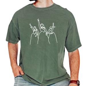 a man wearing a green t - shirt with a drawing of two people holding guns