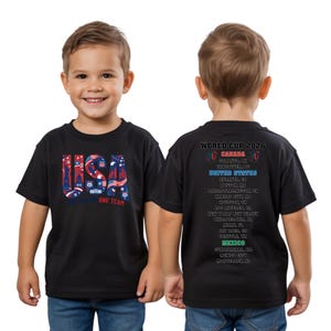 A young boy wearing a black t-shirt with text and graphics printed on it.