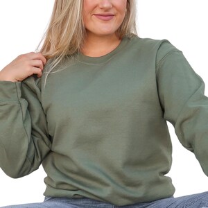 a woman in a green sweatshirt is posing for a picture
