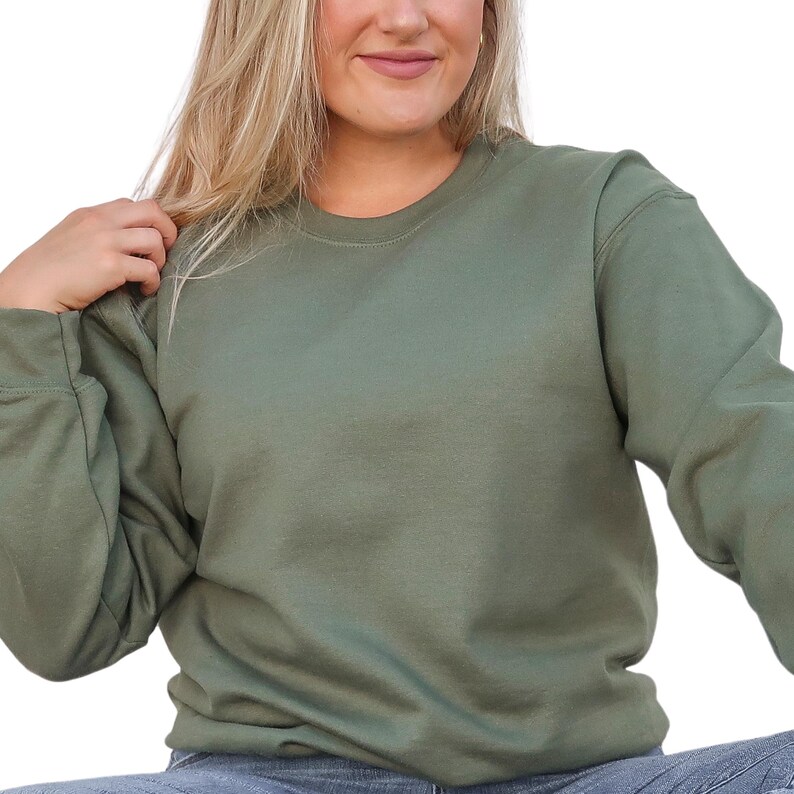 a woman in a green sweatshirt is posing for a picture