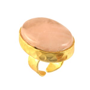 May include: A gold ring with a large oval shaped pink stone set in a hammered gold band.
