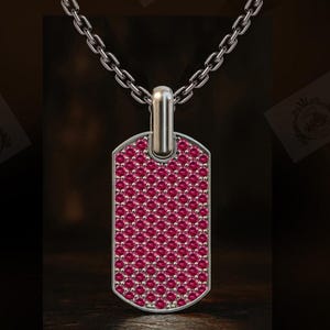 May include: A silver-toned dog tag pendant suspended from a matching silver-toned chain. The rectangular pendant features rounded corners and is densely encrusted with a uniform pattern of small, vibrant pinkish-red circular gemstones.