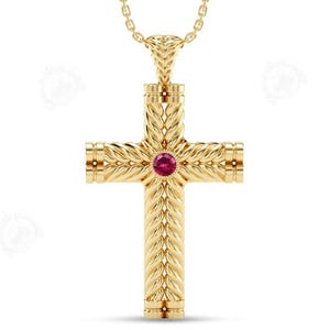 May include: A gold-colored pendant necklace featuring a cross design. The cross has a woven texture and a round, red gemstone at the center. The necklace chain is also gold-colored.