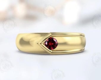 May include: A gold band ring with a single red gemstone set in a V-shaped design.