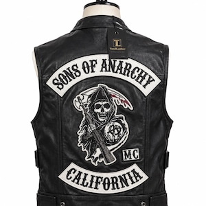May include: A black leather vest featuring a large embroidered back patch with the text SONS OF ANARCHY in white and black. The patch depicts a grim reaper holding a rifle and a scythe, with a smaller MC patch and a CALIFORNIA rocker patch below.