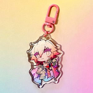Puede incluir: Un llavero de un personaje de anime rosa y blanco con un cierre de metal rosa. El personaje tiene el pelo largo, rosa y blanco, y lleva un atuendo colorido.