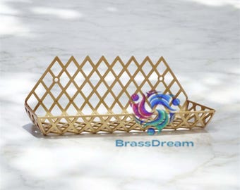 May include: A gold-colored metal tray with a diamond lattice design. The tray has a rectangular shape with a sloped front and sides. The text "BrassDream" is visible on the bottom right.