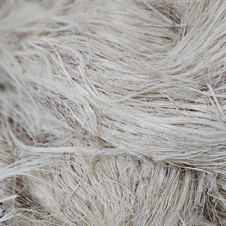 K&ouml;nnte beinhalten: Nahaufnahme eines B&uuml;ndels nat&uuml;rlicher, ungef&auml;rbter Hanffasern. Die Fasern sind hellbeige und haben ein raues, strukturiertes Aussehen. Das Bild hebt die rohe, organische Qualit&auml;t des Materials hervor, das sich f&uuml;r Bastel- oder Textilprojekte eignet.