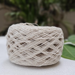 May include: A skein of natural white yarn, wound into a ball shape. The yarn is made of a natural fiber, possibly cotton or linen.