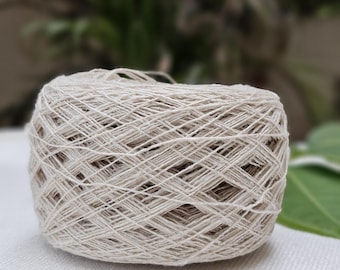 May include: A skein of natural white yarn, wound into a ball shape. The yarn is made of a natural fiber, possibly cotton or linen.